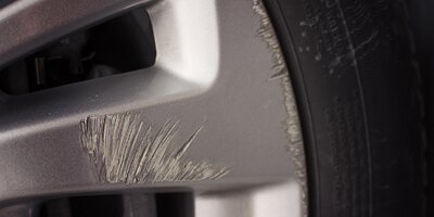 Scuffed alloy wheel with scratches across a spoke