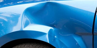 Large dent in the wing of a blue car