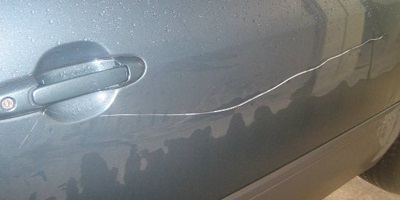Long scratch running along a grey car door below the handle